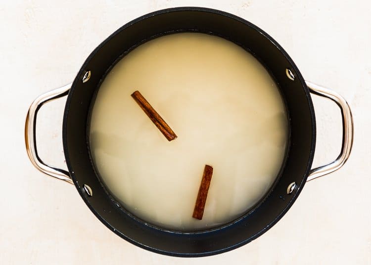 rice, water and two cinnamon sticks in a pot.