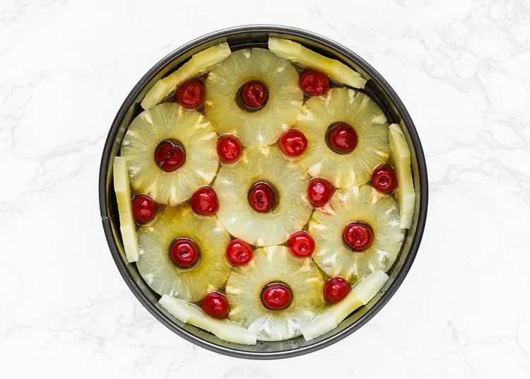 melted butter and brown sugar mix together in a cake pan and topped with pineapple rings and cherries. 