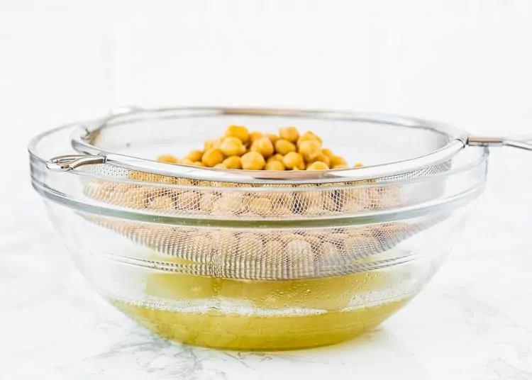 canned chickpeas being drain into a bowl. 