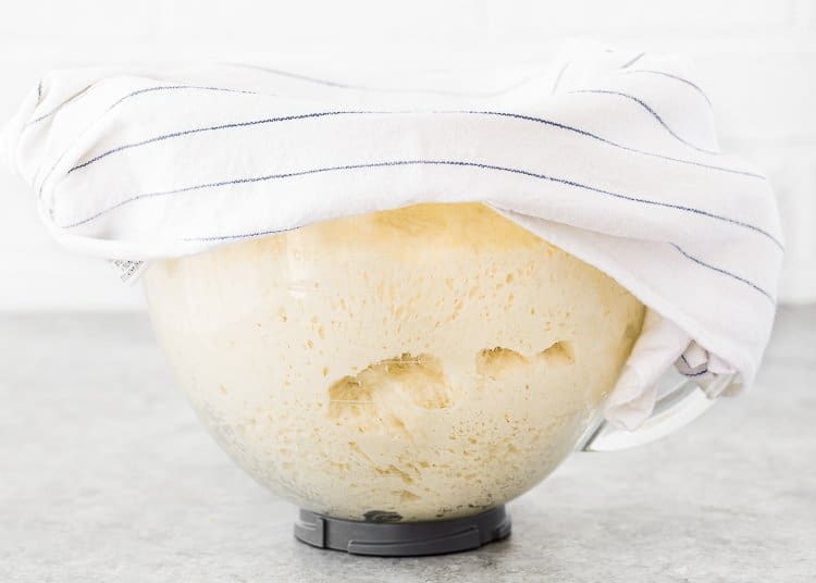 risen egg-free Hawaiian rolls dough in a stand mixer bowl cover with a kitchen towel. 