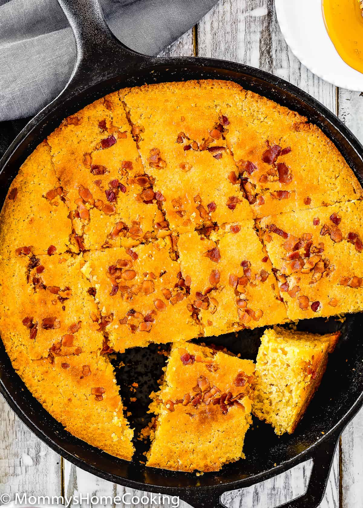 overhead view of eggless cornbread cut into portions in a cast iron skillet