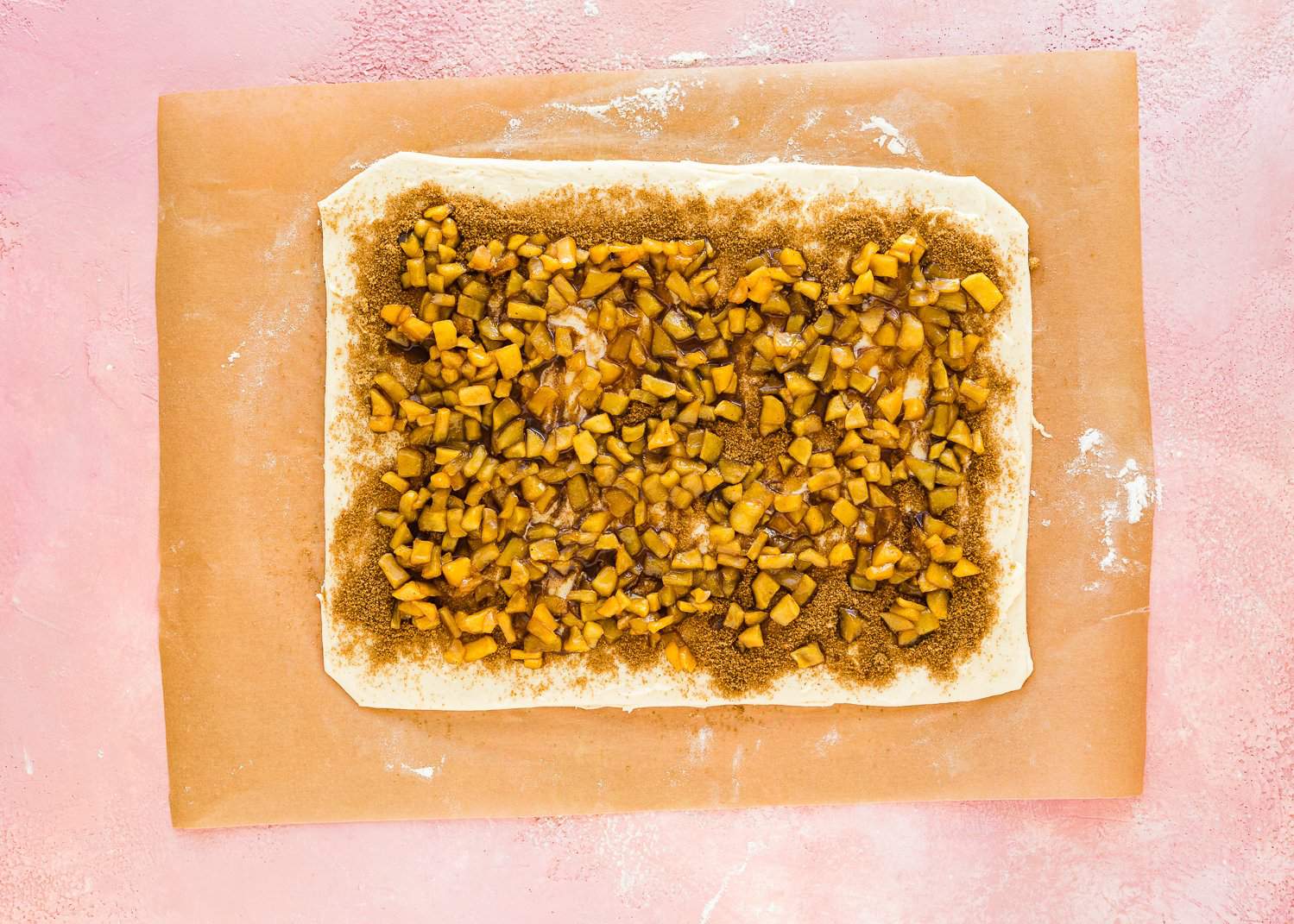 egg-free dough rolled into a rectangle with butter and cinnamon sugar on top over parchment paper. 