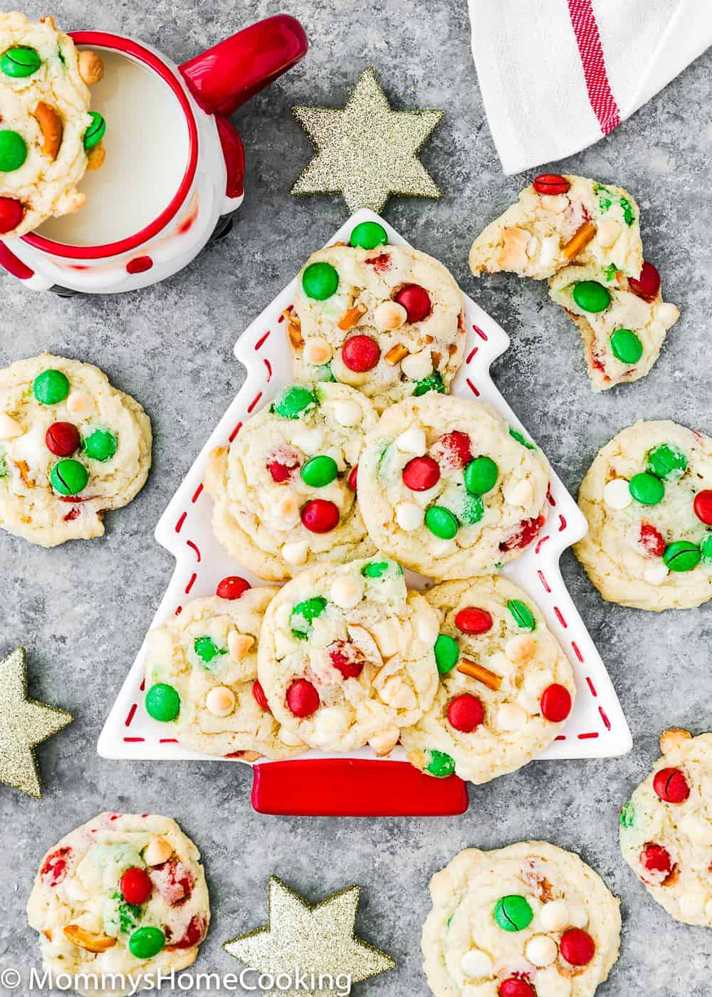 eggless Christmas cookies on a tree shaped plate over a gray surface with more cookies around it. 