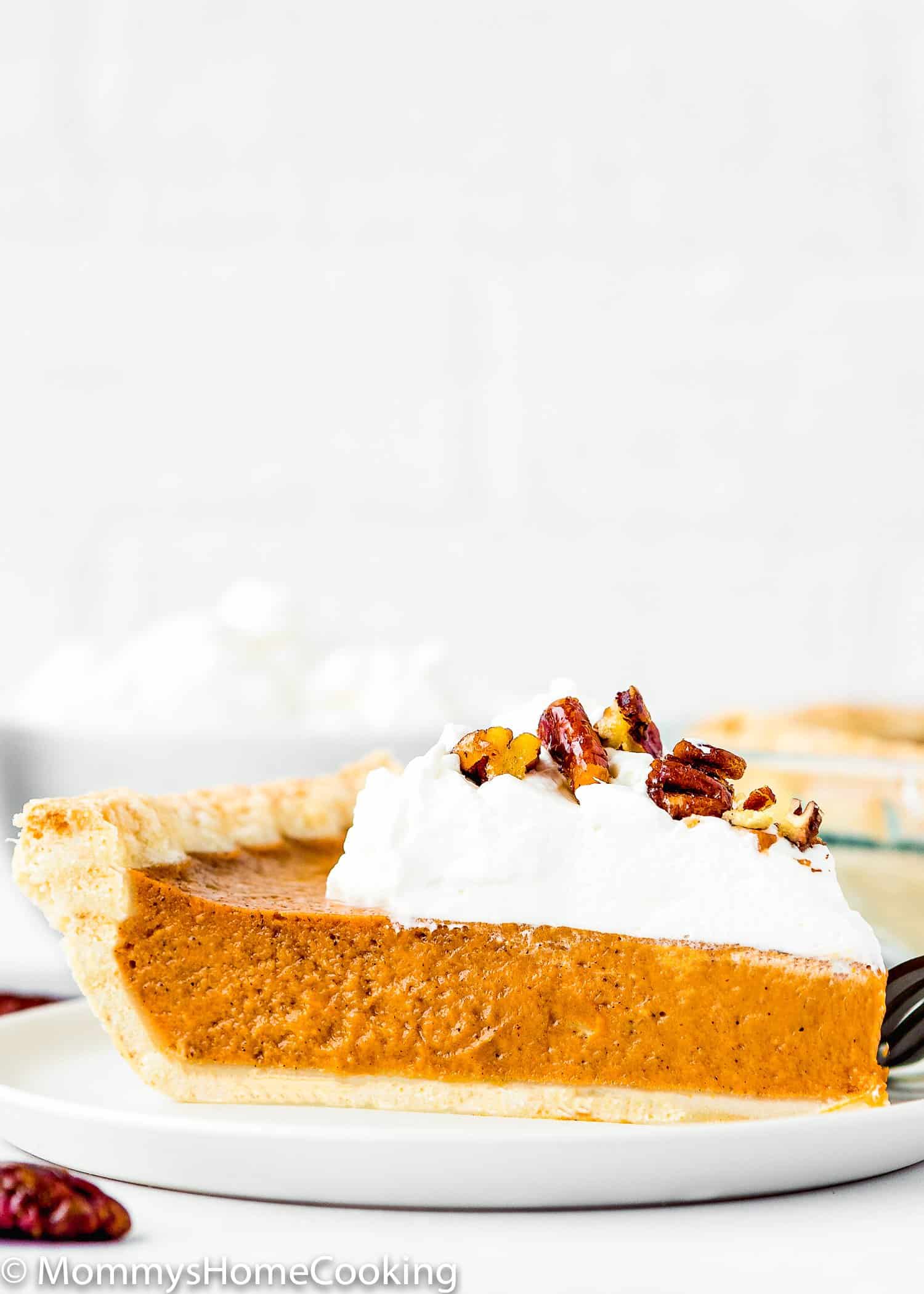 egg-free sweet potato pie slice on a plate with whipped cream and pecan. 