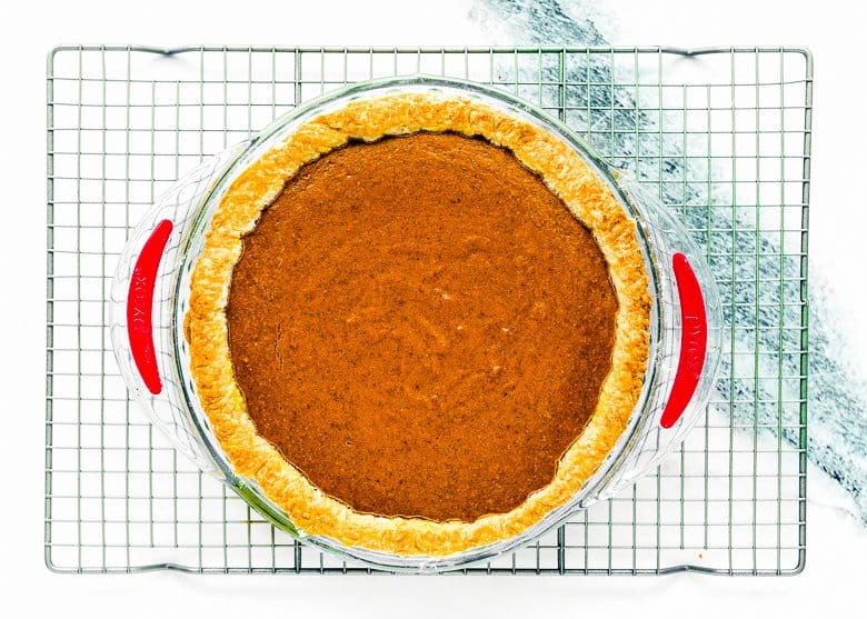 baked sweet potato pie in a pie dish over a cooling rack. 