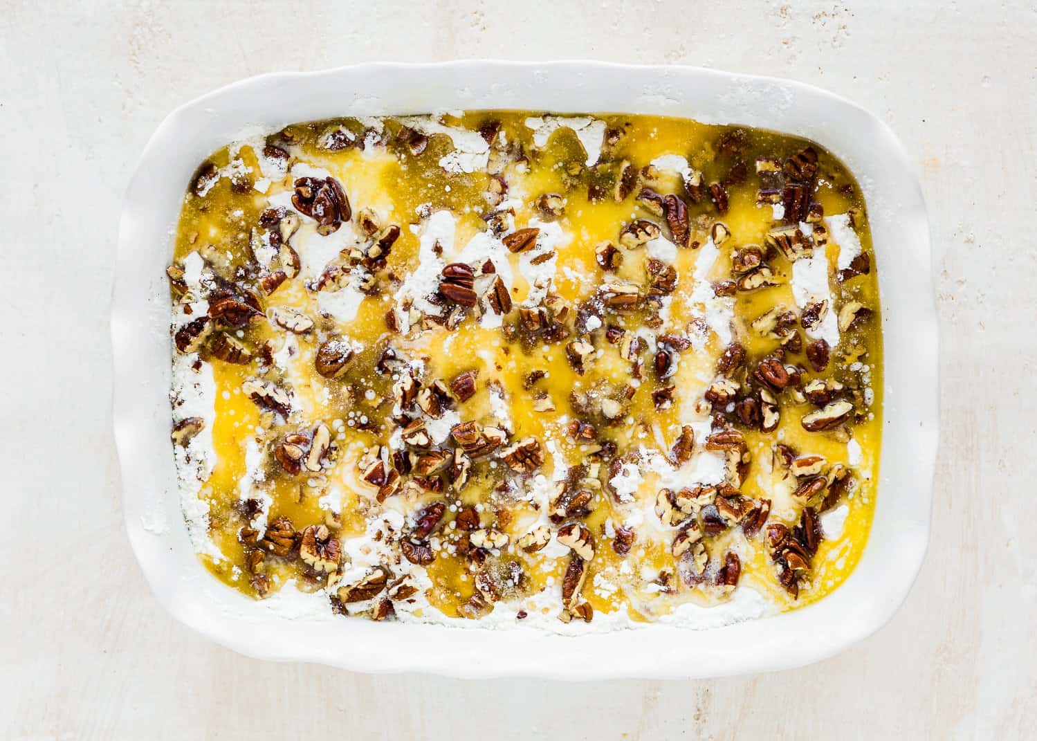 eggless dump cake mixture in a baking dish with a cake mix and pecans and melted butter sprinkled on top.