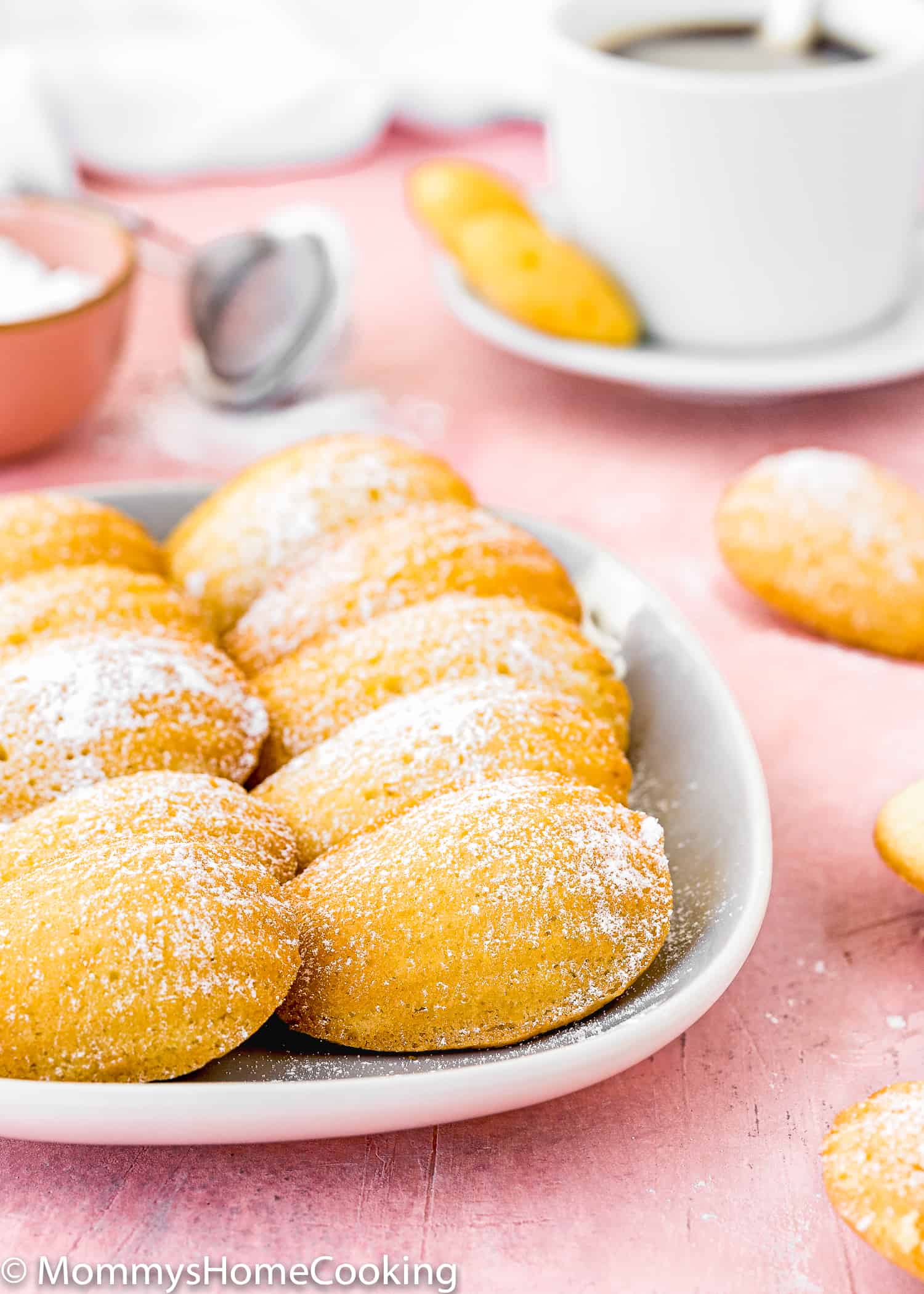 egg-free madeleines on a plate sprinkled with powdered sugar. 