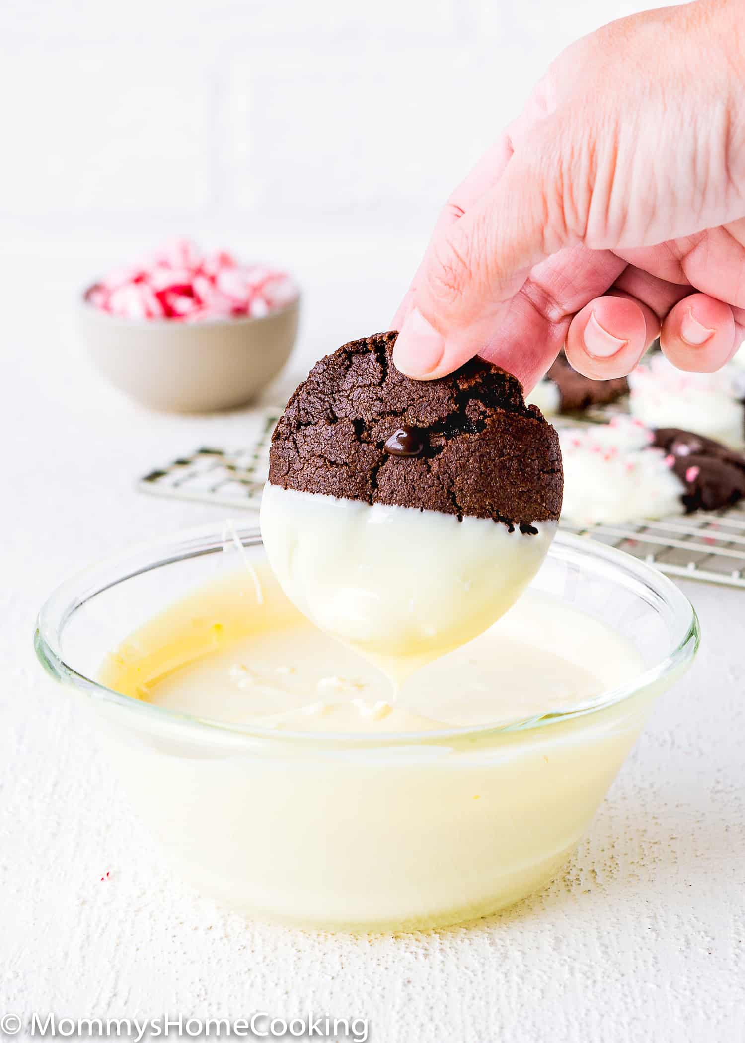 dipping a Eggless Triple Chocolate Peppermint Cookie in melted white chocolate