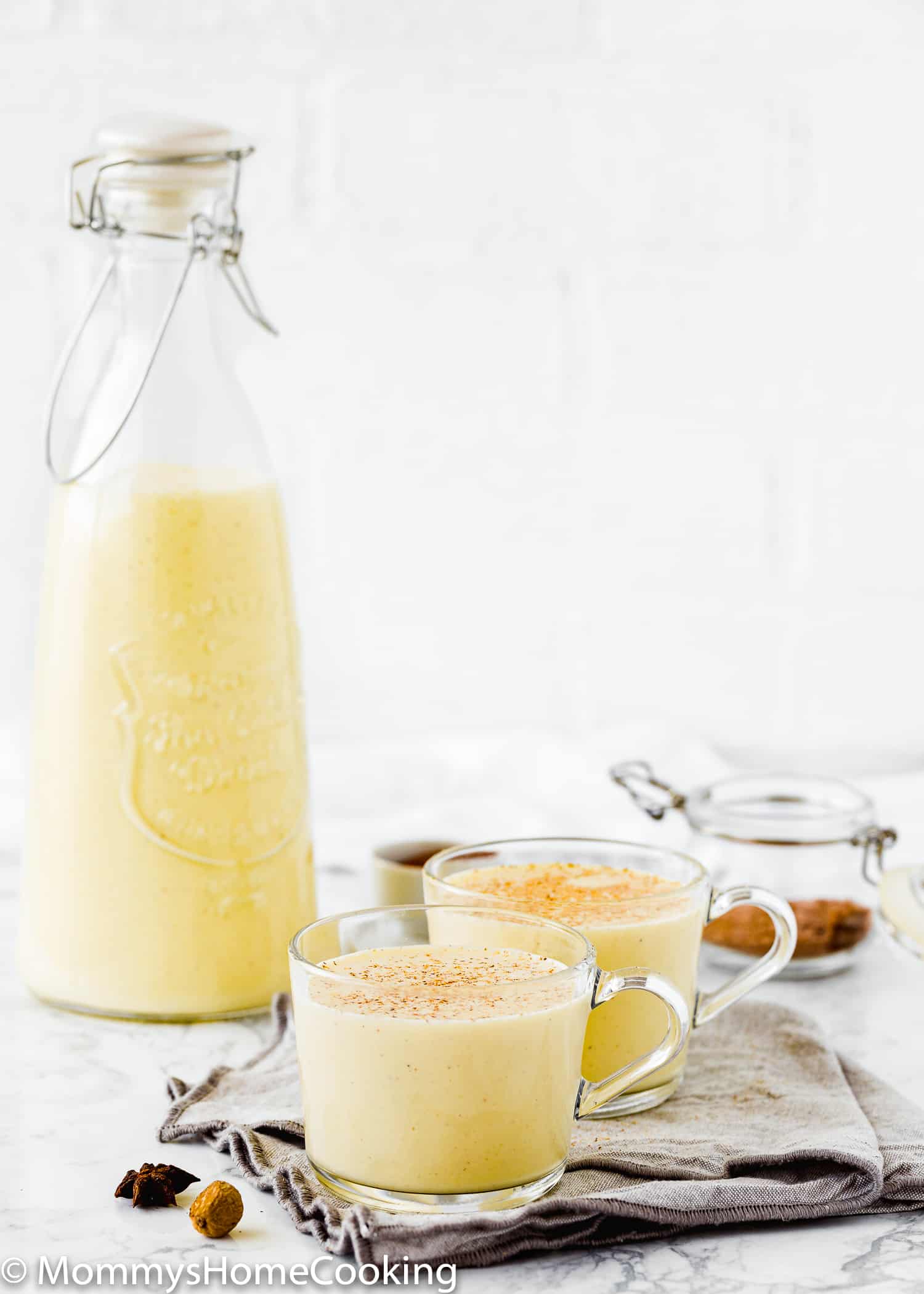 two glasses with egg-free nog over a gray kitchen towel.