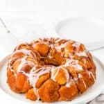 Homemade Eggless Monkey Bread on a plate drizzled with sugar glaze on a plate.