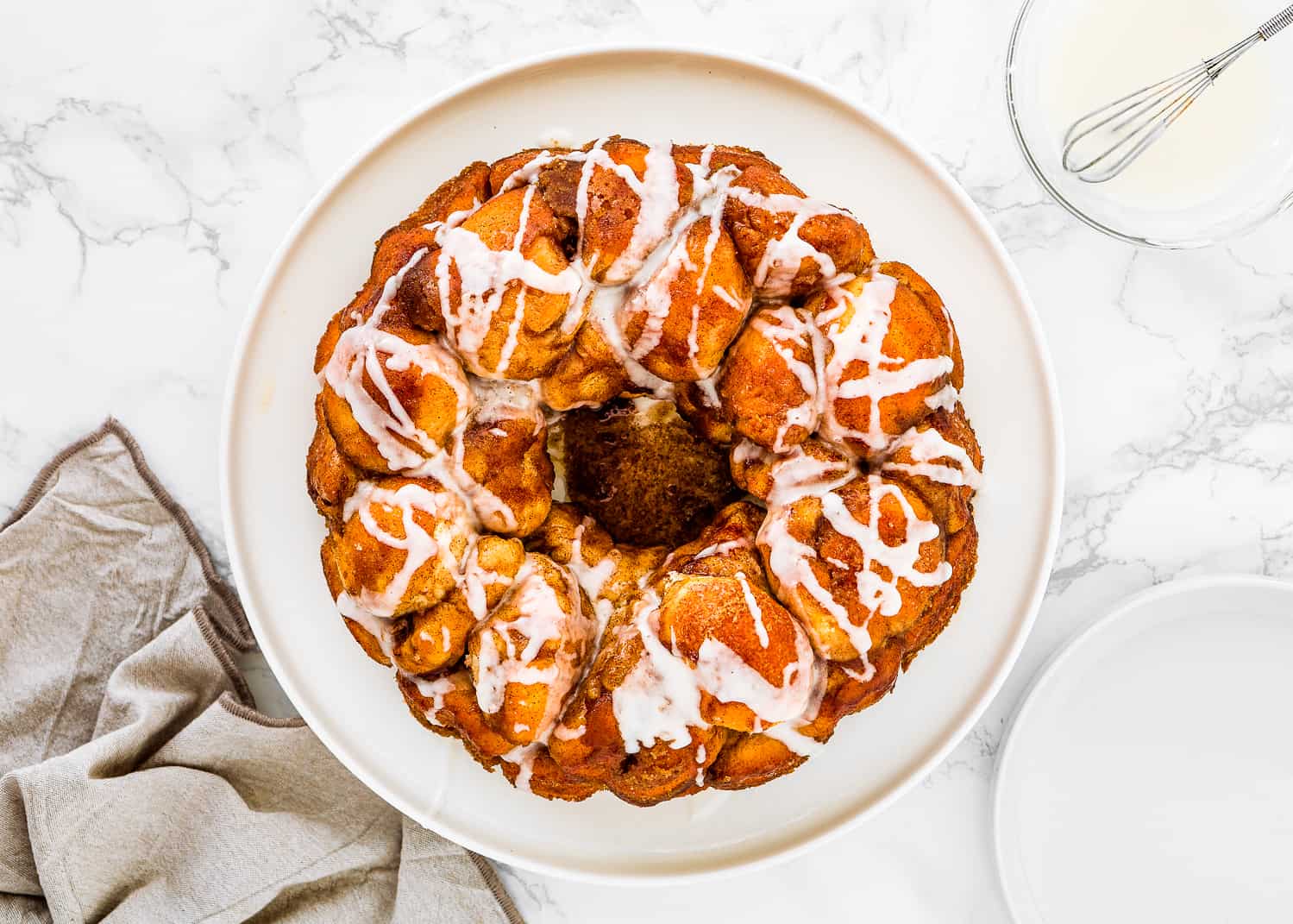 Egg-free monkey bread on a plate drizzle with glaze. 