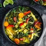 detox soup in a bowl with lime wedges on the side.