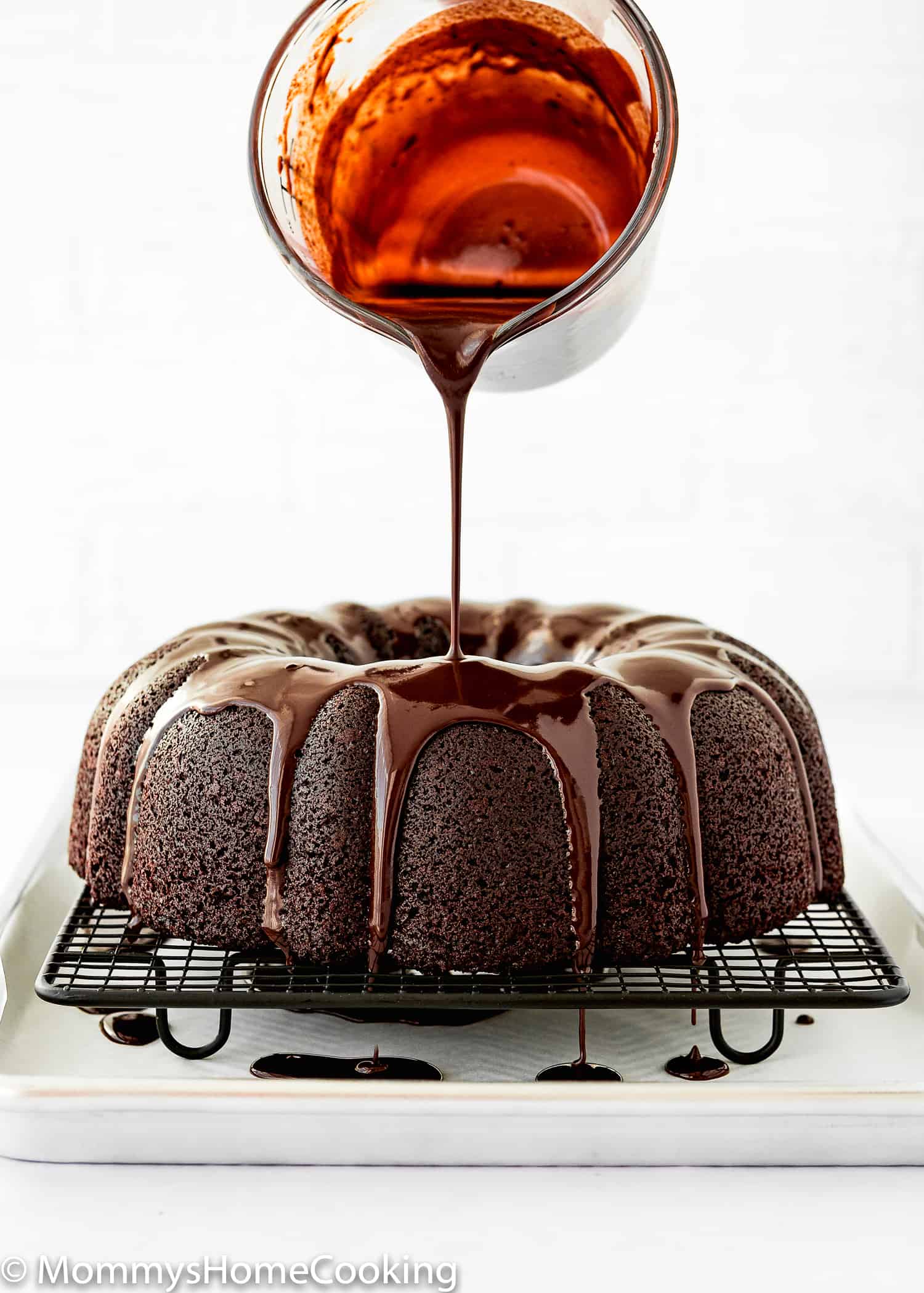 chocolate glaze being poured over a Eggless Chocolate Bundt Cake.