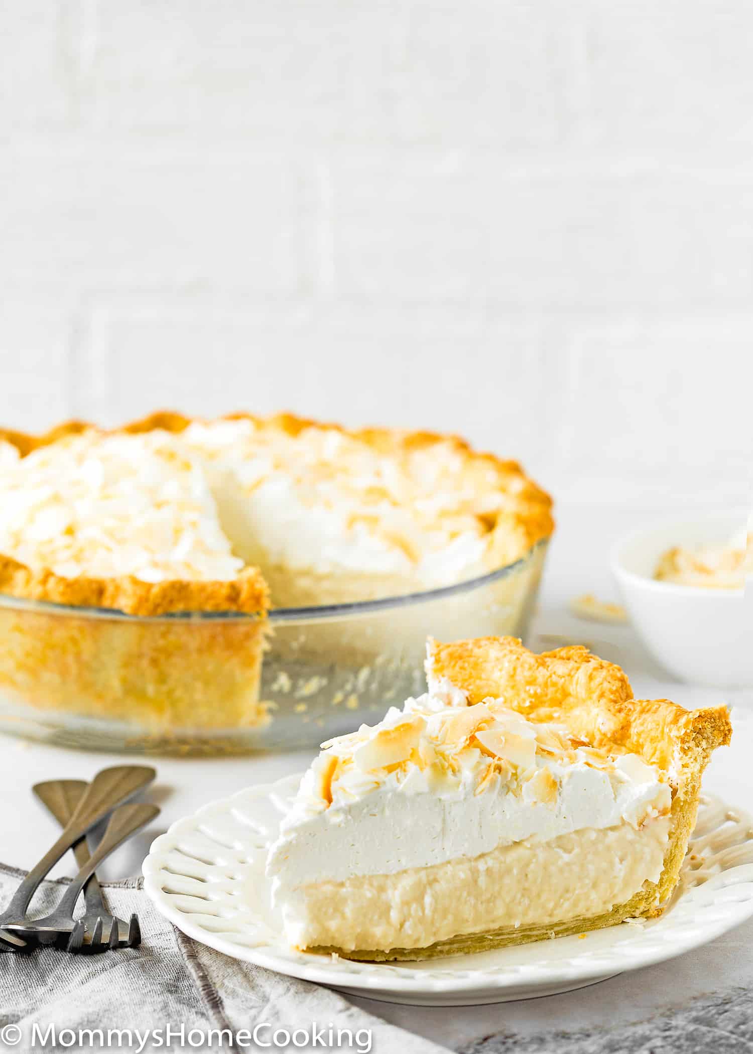a slice of Eggless Coconut Cream over a white plate with the whole pie in the background.
