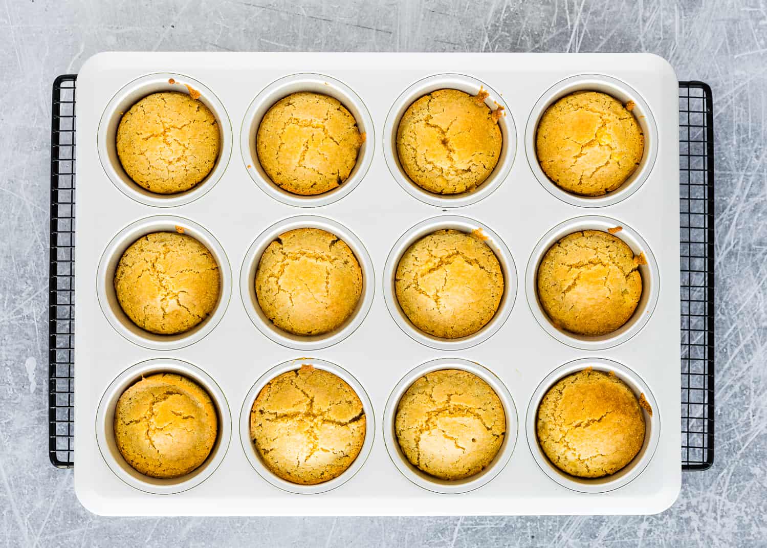 baked  Eggless Cornbread Muffins in a muffin pan over a cooling rack. 