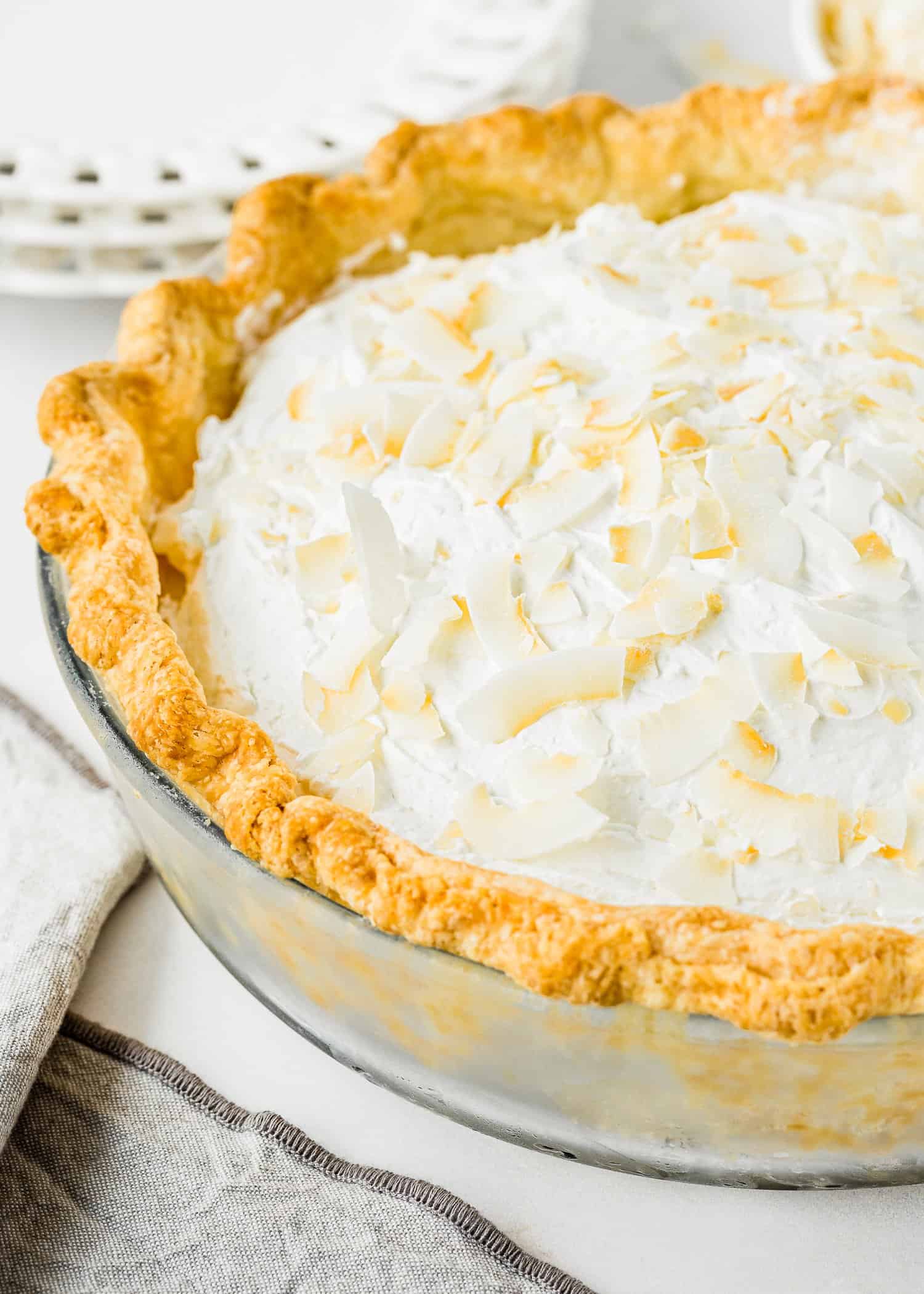 Eggless Coconut Cream Pie topped with whipped cream and toasted coconut in a pie dish.