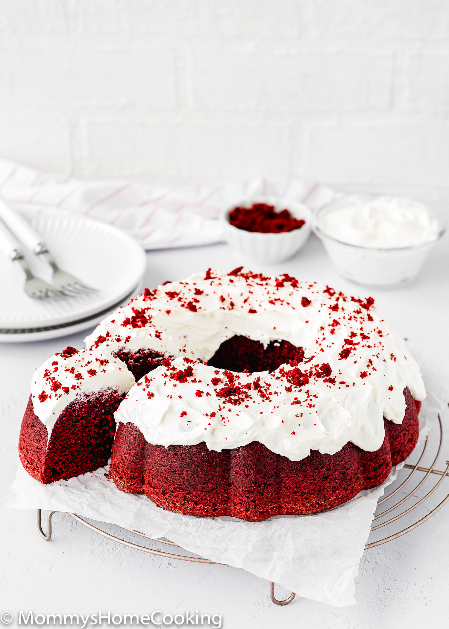 Eggless Red Velvet Bundt Cake with cream cheese frosting over a cooling rack