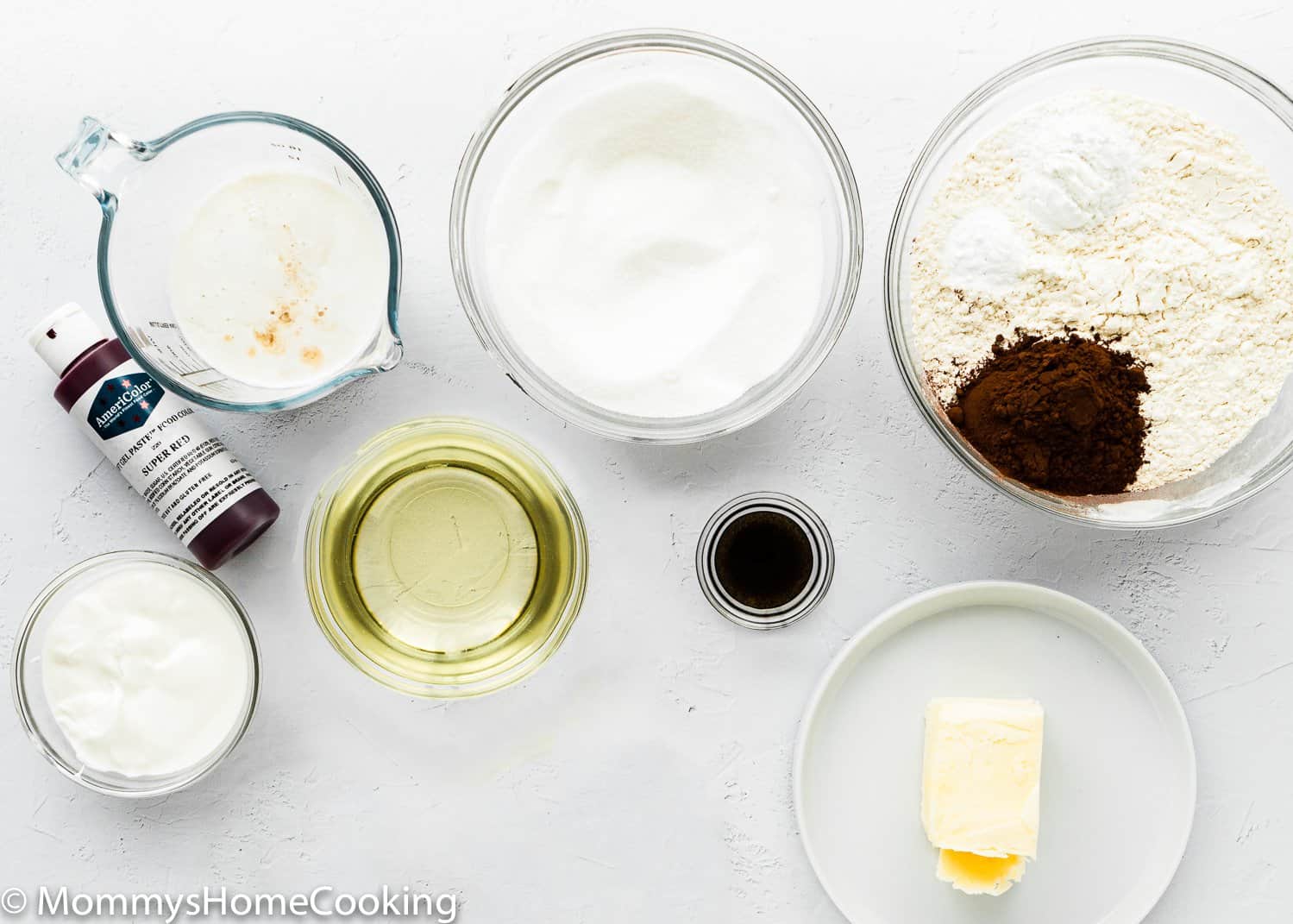 ingredients to make an eggless cake over a white surface 