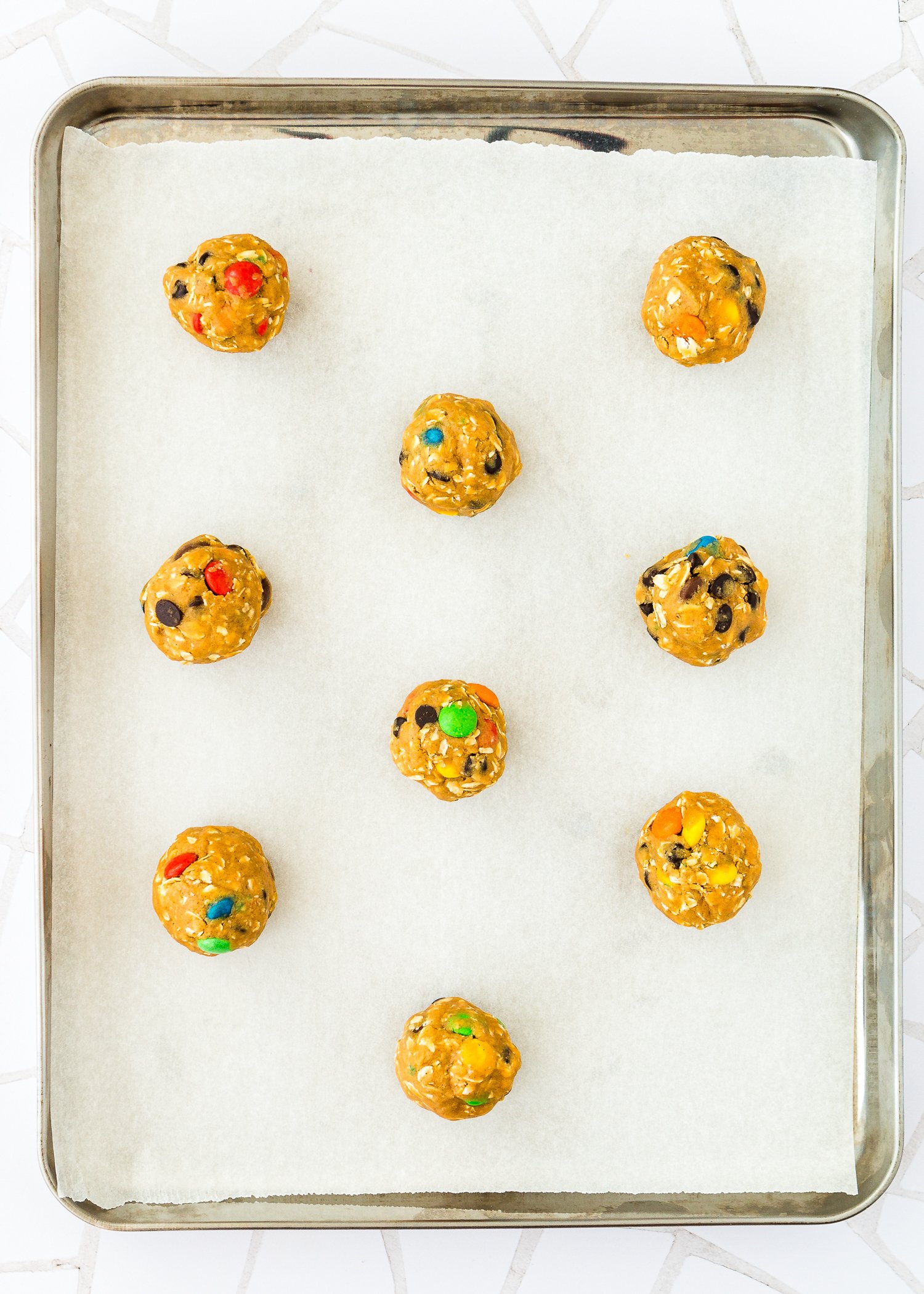 Eggless Monster Cookies dough balls on a baking tray. 