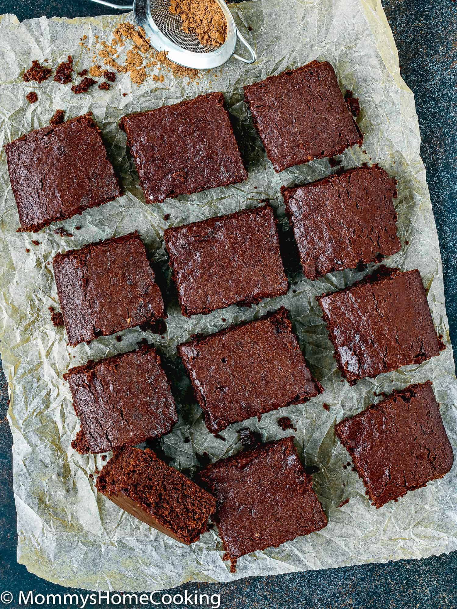 A batch of egg-free brownies cut on top of a piece of parchment paper.