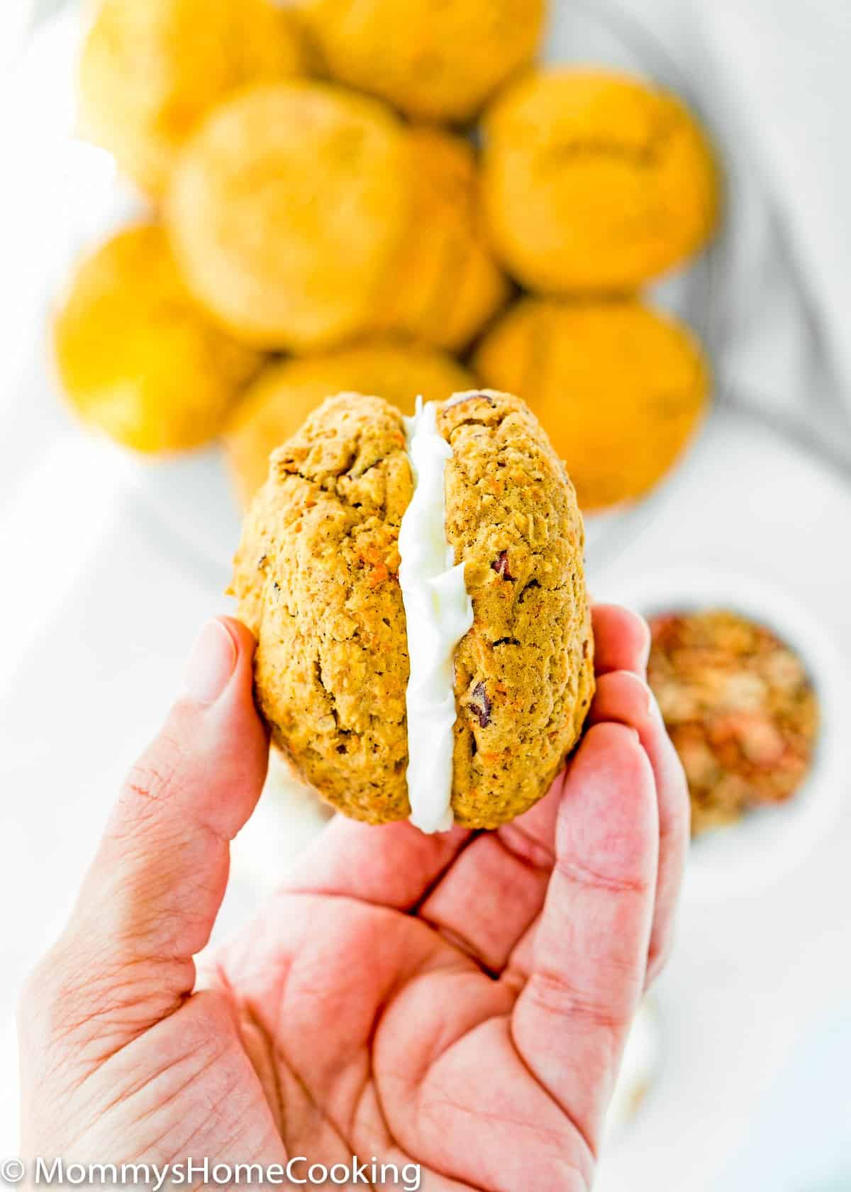 a hand holding a Eggless Carrot Cake Cookie sandwich