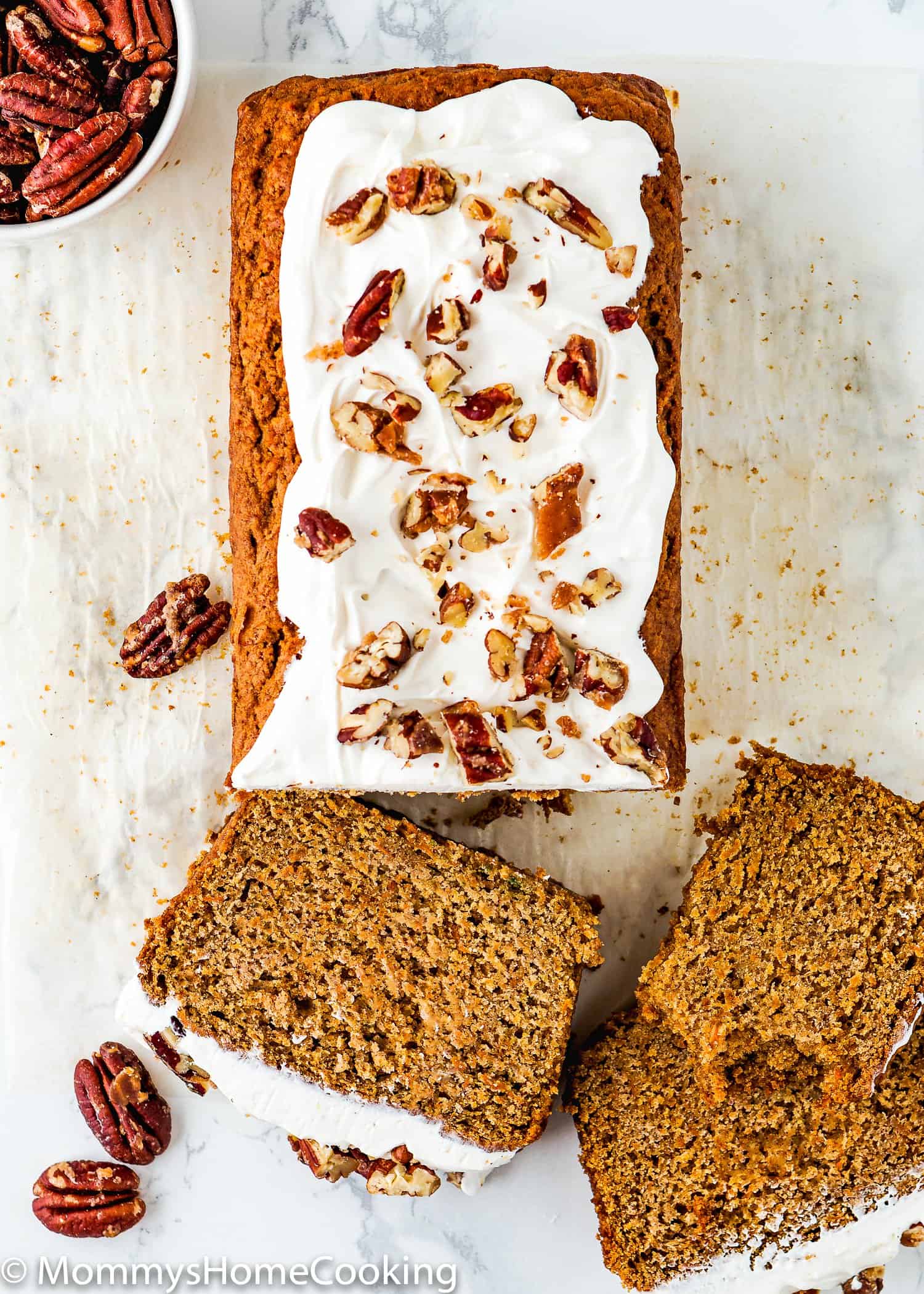 sliced Eggless Carrot Cake Loaf with frosting and pecans on top. 