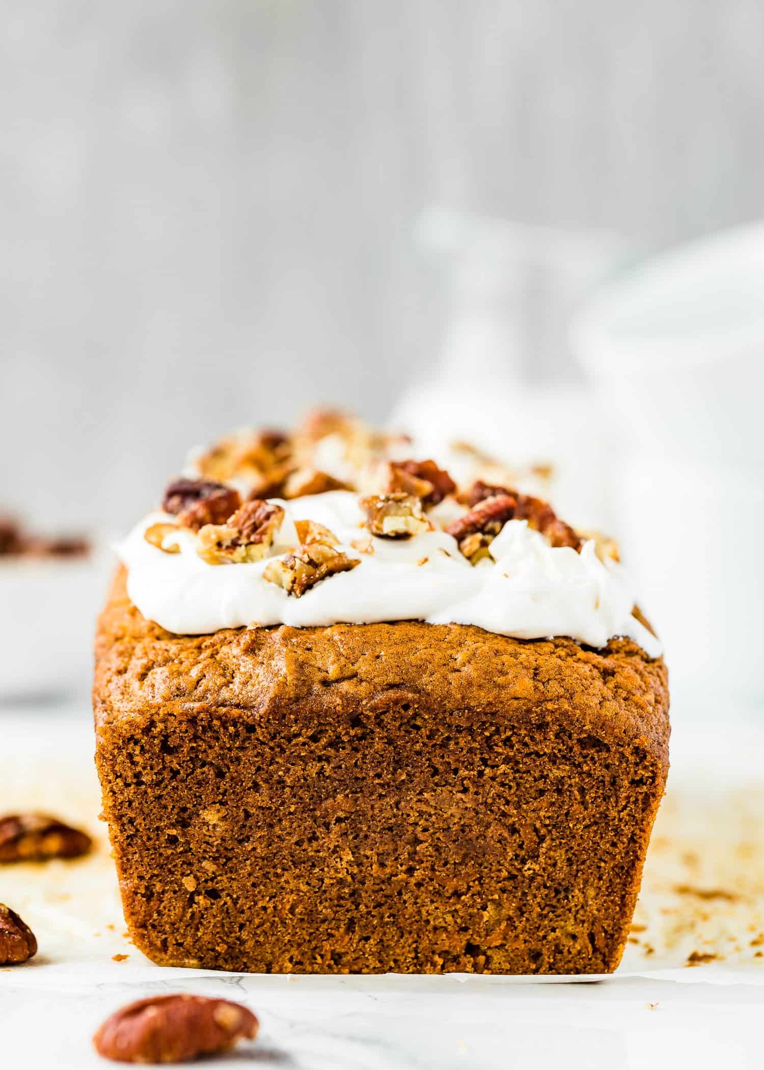 Eggless Carrot Cake Loaf frosted with cream cheese frosting and pecan