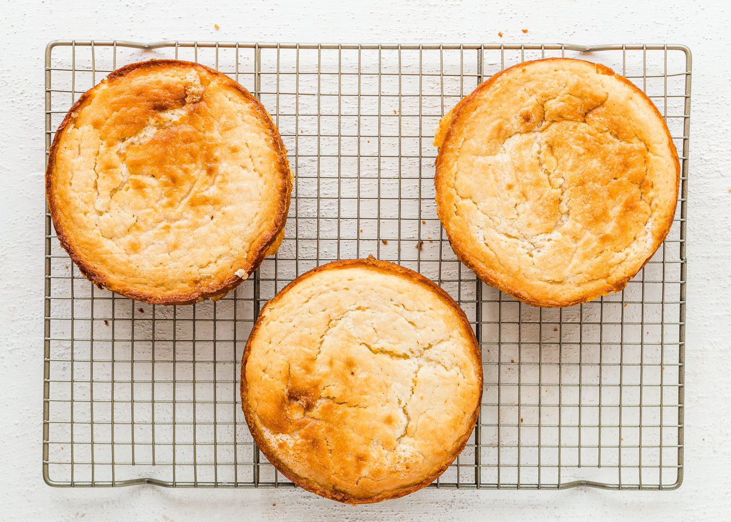 three lemon layer cakes over a cooling rack