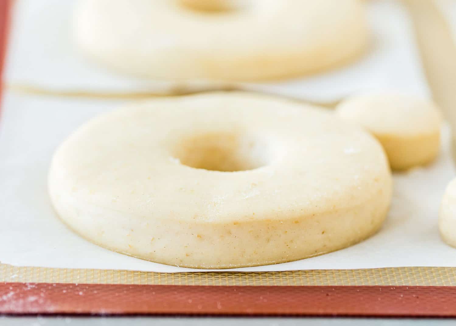 unfried risen egg-free donuts over a silicone mat. 