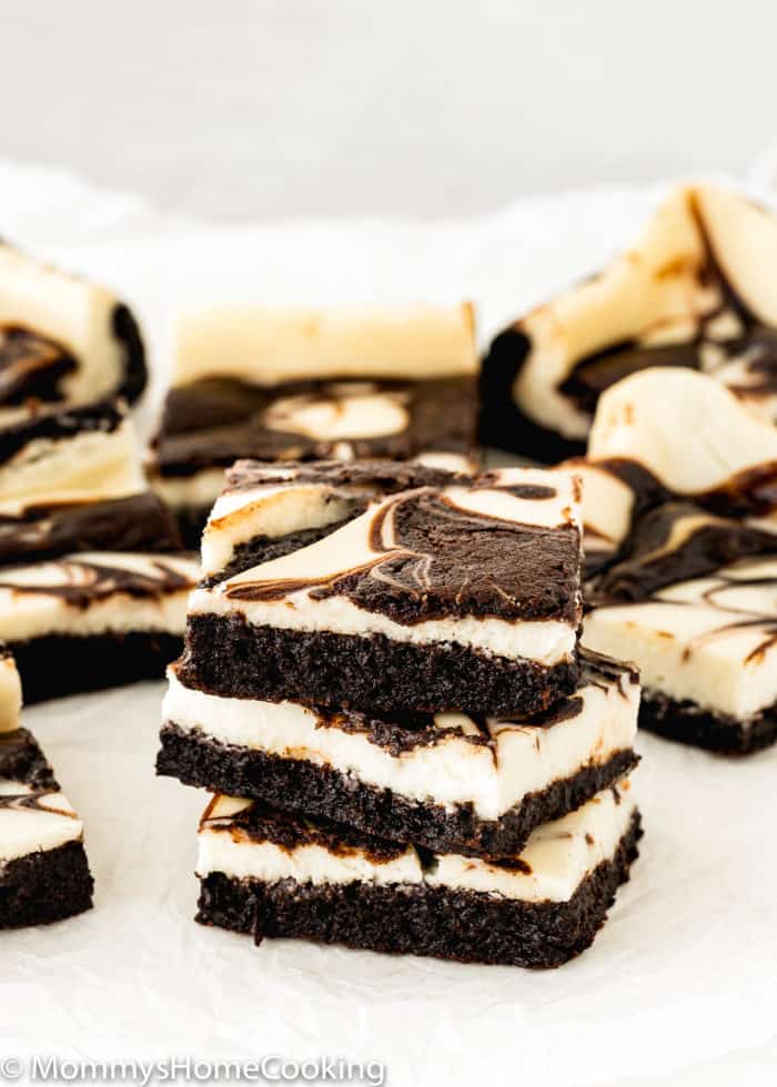 stack of three eggless cheesecake brownies over parchment paper