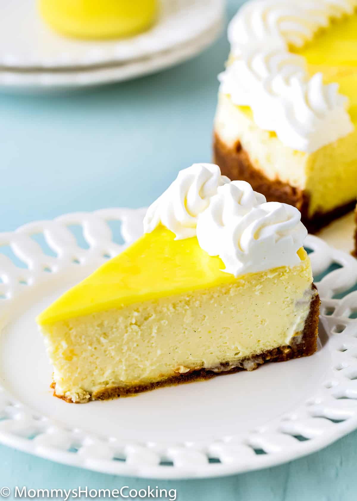 a slice of egg-free lemon cheesecake on a white plate. 