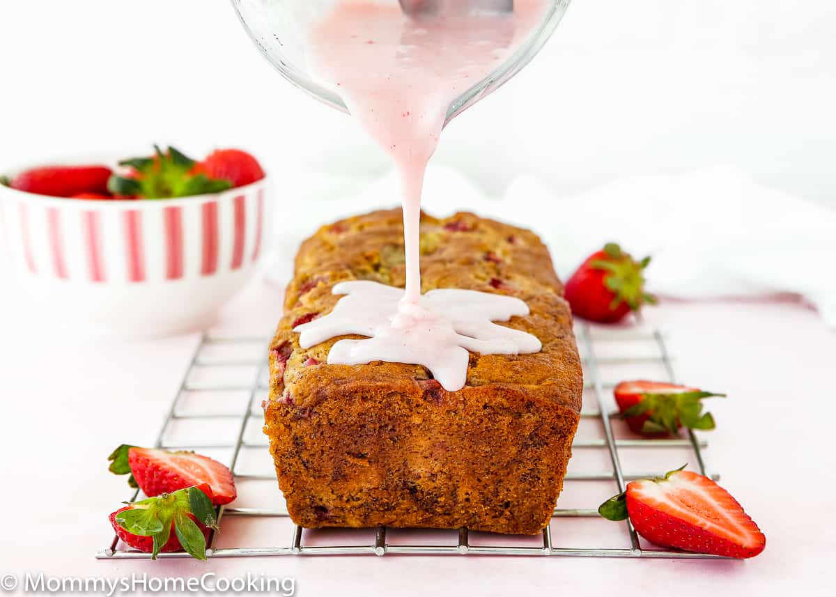 strawberry sugar glaze being poured over a Eggless Strawberry Banana Bread.