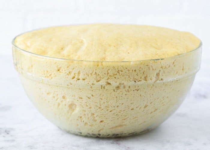 a risen egg-free brioche dough in a bowl.