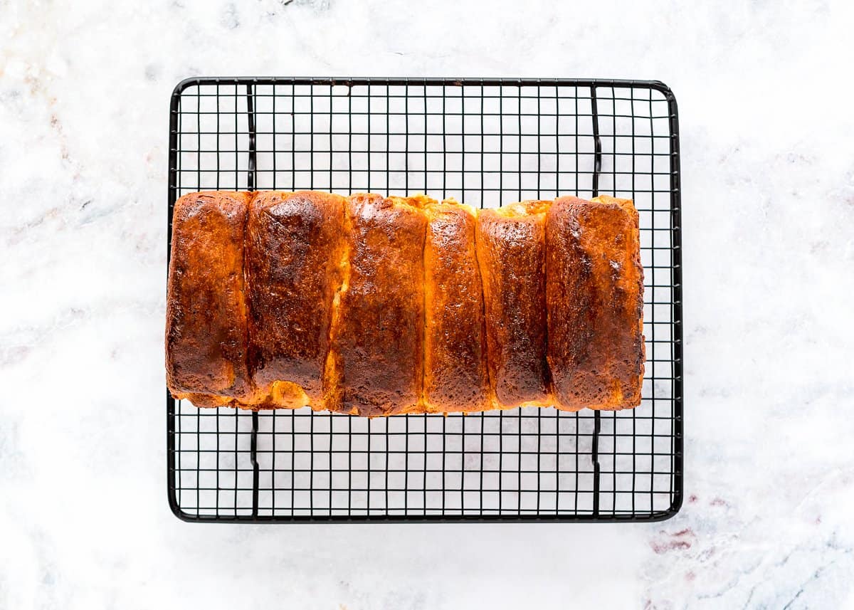 a baked egg-free brioche loaf over a cooling rack.  