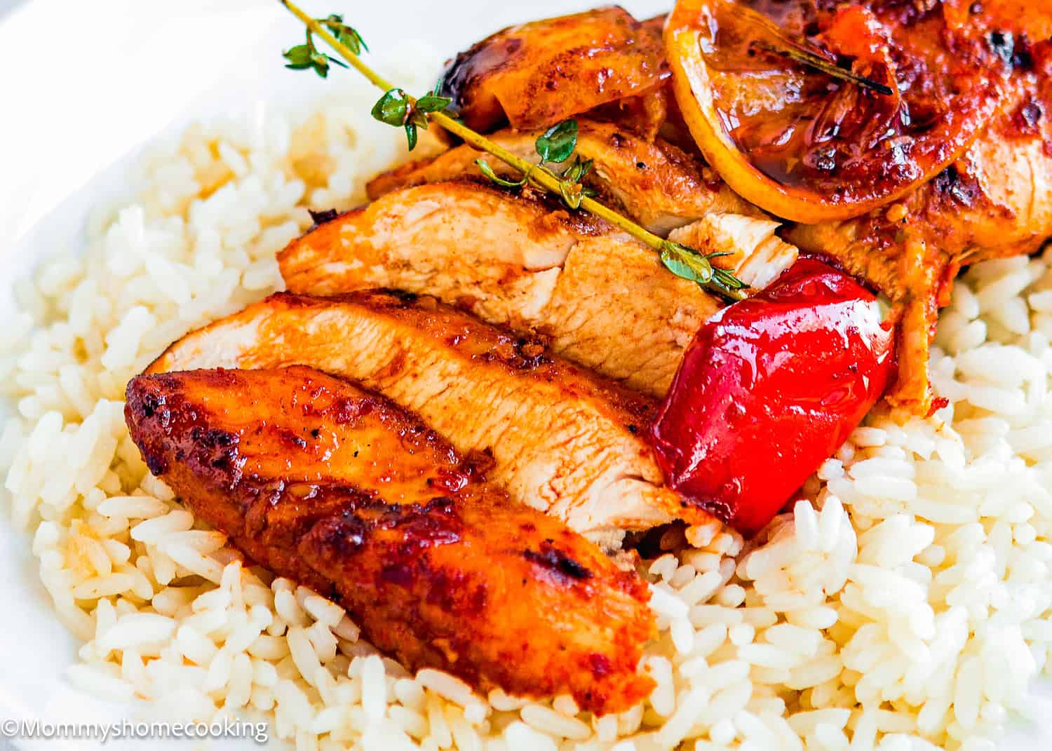 Sliced grilled chicken breast with herbs, lemon, and red pepper served over a bed of white rice—featuring the juiciest peri peri chicken breasts (one skillet) for an extra kick of flavor.
