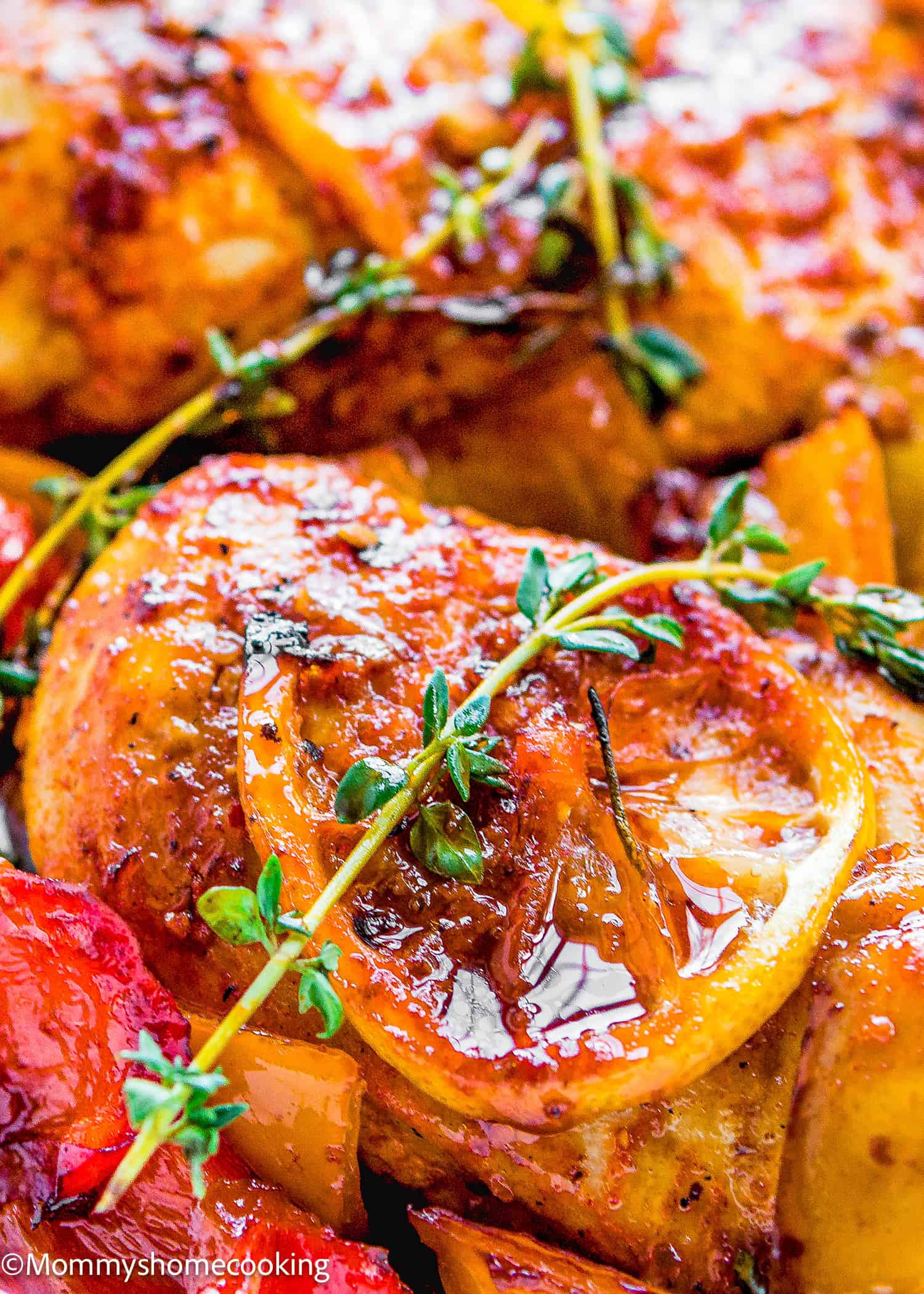 Close-up of The Juiciest Peri Peri Chicken Breasts (One Skillet), garnished with lemon slices, fresh thyme, and cooked red bell peppers.
