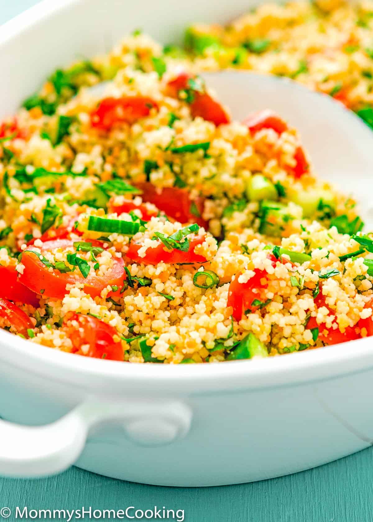 couscous, cucumbers, tomatoes, mint, and parsley salad in a bowl with a serving spoon
