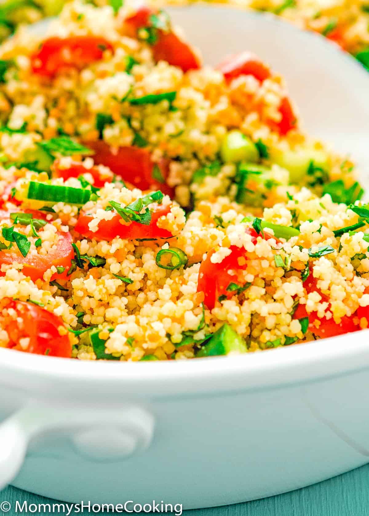 Close up of a salad with couscous, cucumbers, tomatoes, mint, and parsley. 