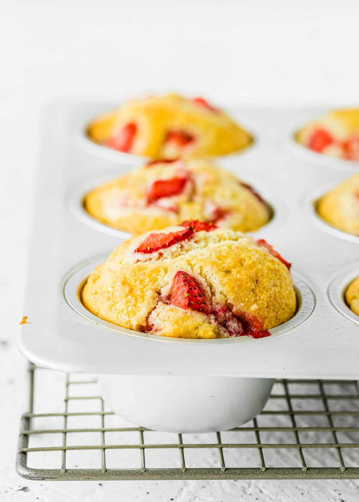 baked egg-free strawberry muffins in a muffin pan over a cooling rack.