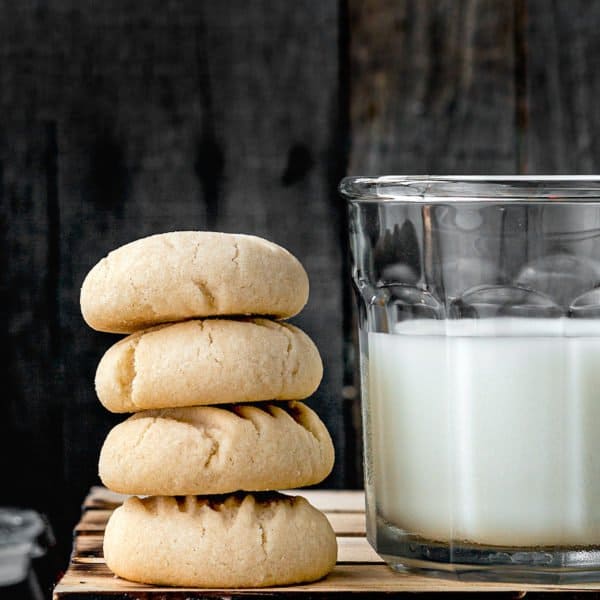 stack of venezuelan polvorosas cookies with a glass of milk
