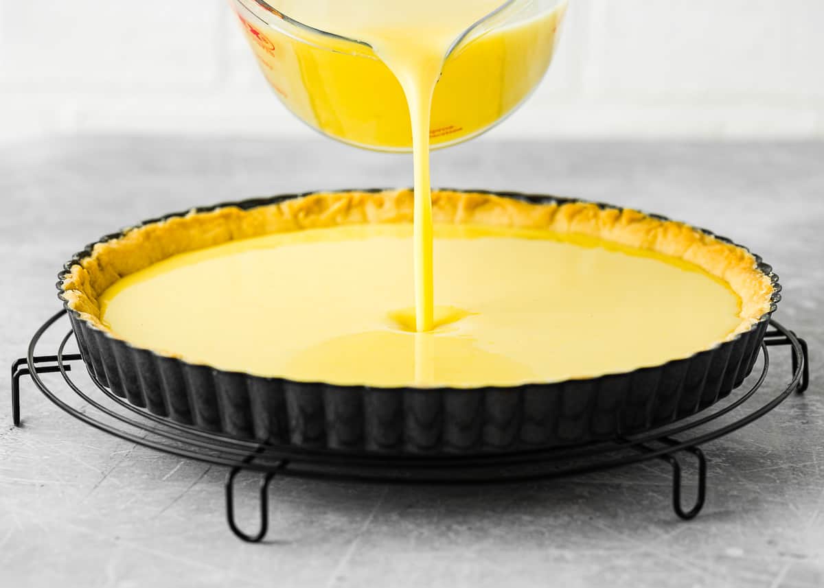 eggless lemon curd filling being poured into an eggless tart crust