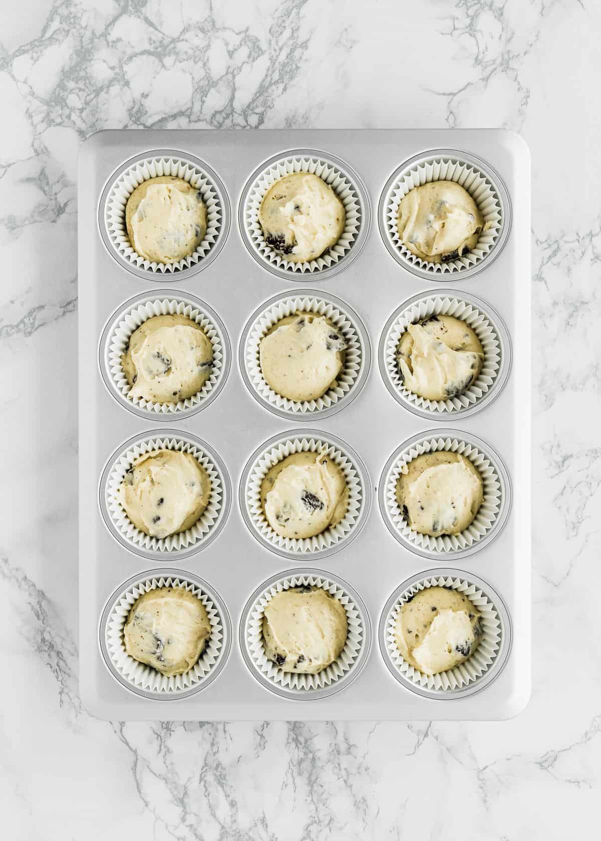 a cupcake pan with liners filled with eggless oreo cupcakes batter.