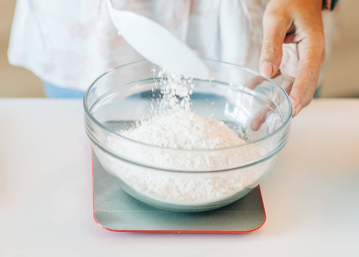 a women measuring flour with a kitchen scale