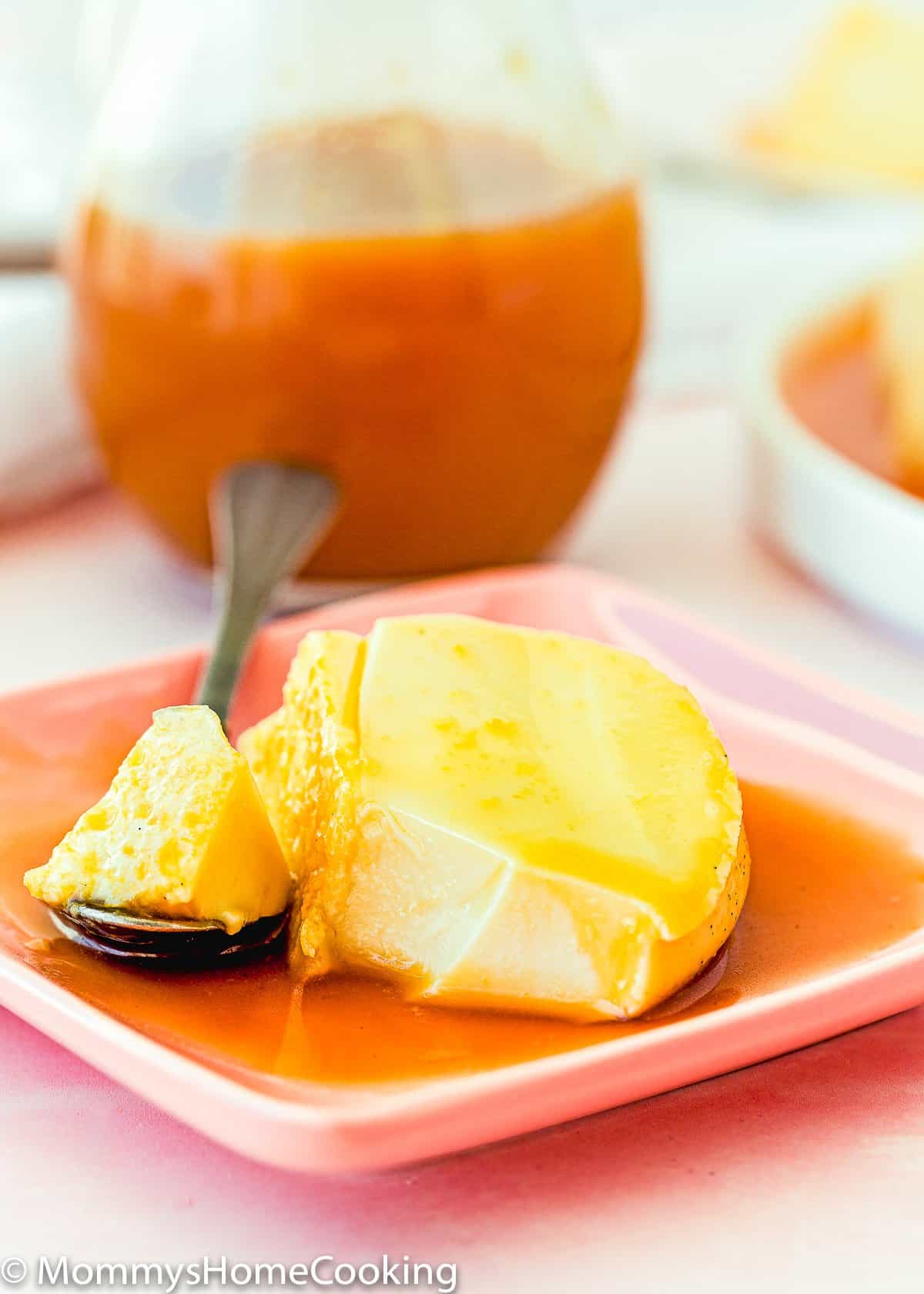 a slice of eggless flan on a plate with a spoon and caramel sauce.