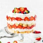 Eggless Berry Trifle Cake over a marble surface with fresh berries around