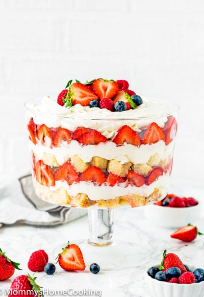 Eggless Berry Trifle Cake over a marble surface with fresh berries around