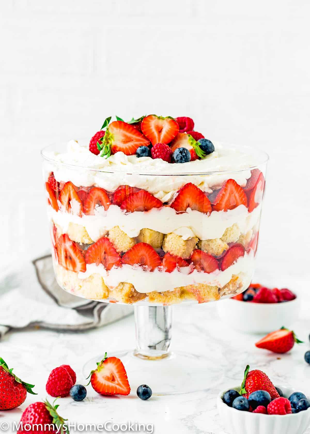 Eggless Berry Trifle Cake over a marble surface with fresh berries around.