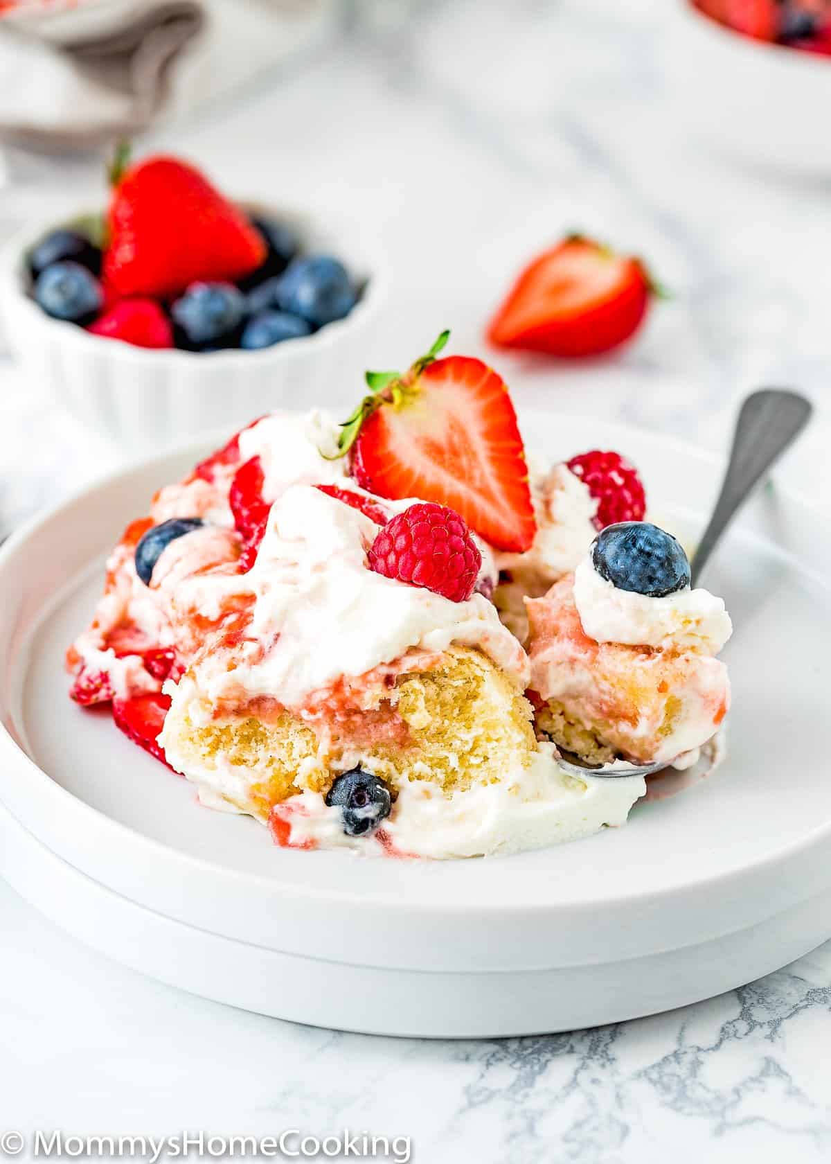 Eggless Berry Trifle Cake on a plate with a spoon.