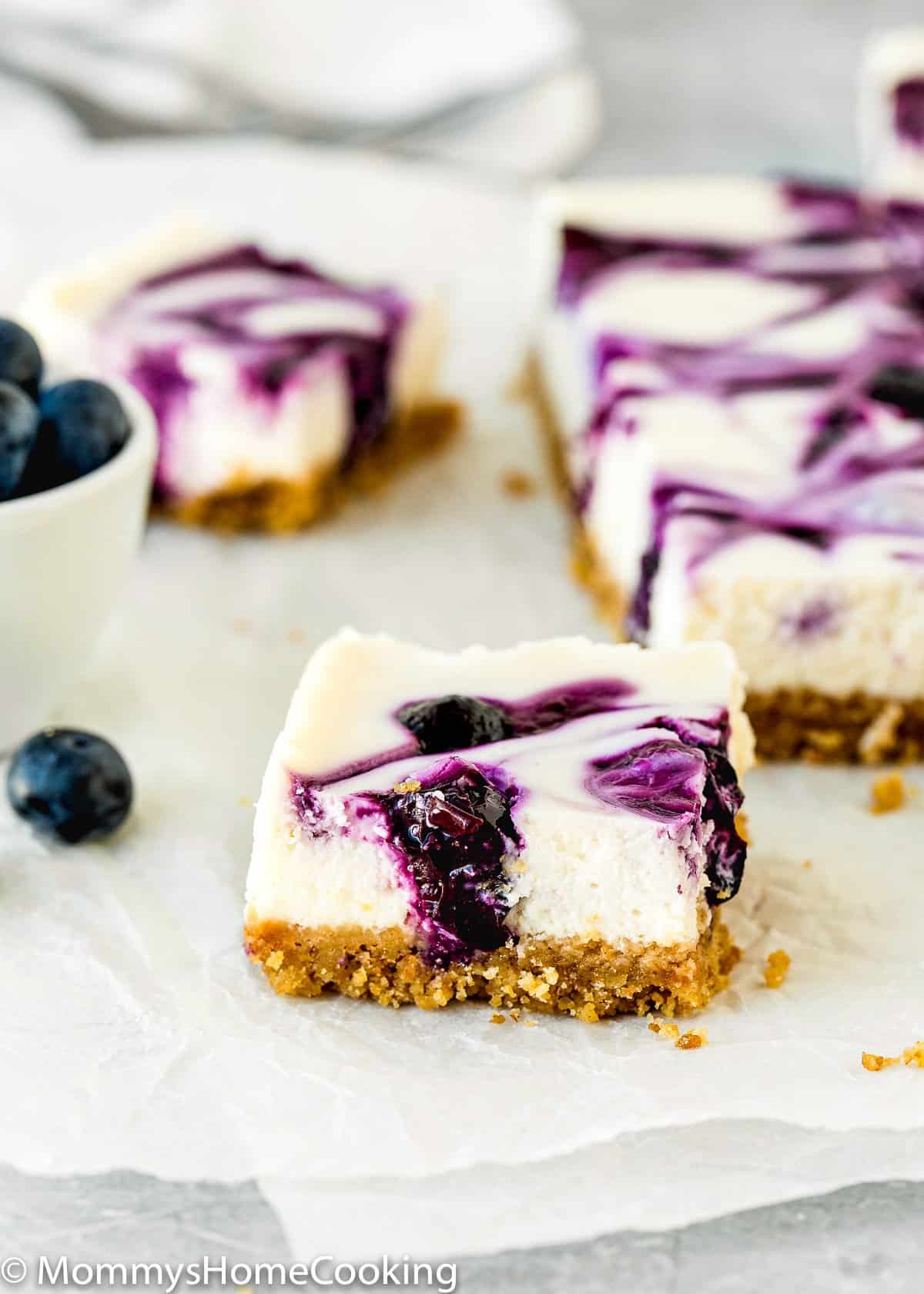 Eggless Lemon Blueberry Cheesecake Bar over a piece of parchment paper