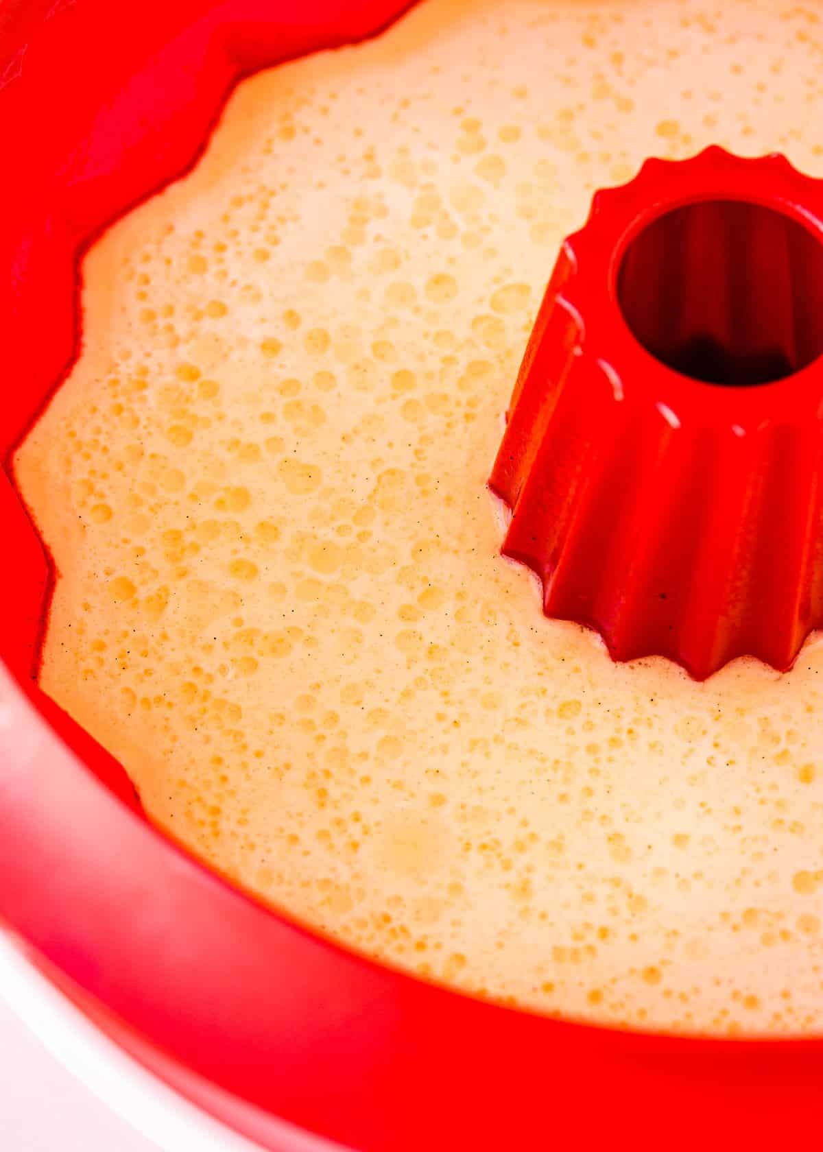 close up view of an eggless flan in a red silicone mold.